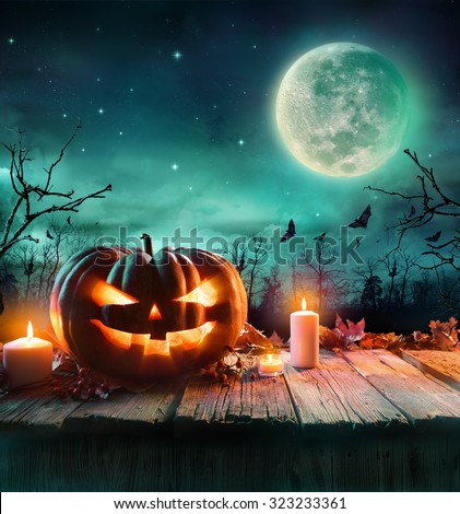 Halloween Pumpkin On Wooden Plank With Candles In A Spooky Night
