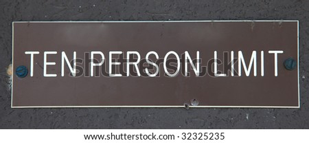 Worn sign reading Ten Person Limit in white print over brown.