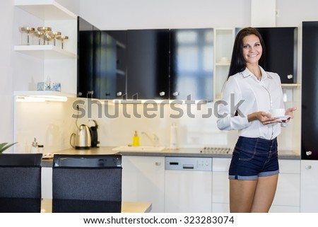 Beautiful woman holding a cup in a kitchen and smiling