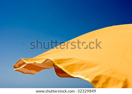 Orange beach umbrella over blue sky background. Space for copy. Jpeg file with clipping path included.