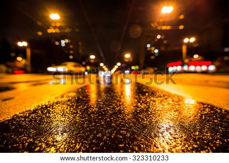 Night city after rain, the glowing lights of approaching cars. Wide angle view of the level of the pedestrian crossing