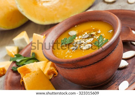 Pumpkin soup with oil and seeds in a clay bowl in a rustic style, selective focus