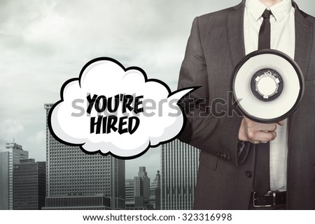 Youre hired text on speech bubble with businessman and megaphone on city background 