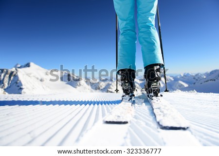 Girl on ski standing on the fresh snow on newly groomed ski piste at sunny day in mountains