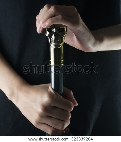 Staff with skull Holding in woman hand on black background , Witch