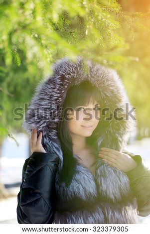 Winter woman on background of winter landscape sun. Fashion girl in forest wonderland. Winter sunset scene. Model in sunlight, backlight