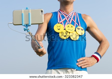 Athlete taking selfie wearing gold medals with bright yellow emoji faces with smartphone on selfie stick