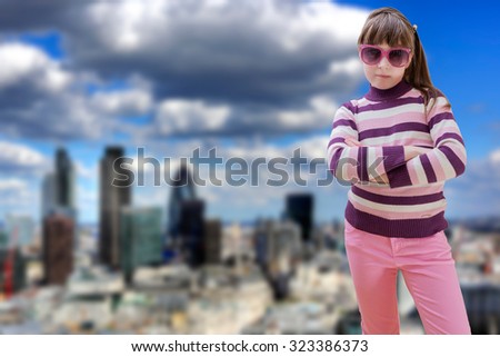 Teenage girl in pink wears sunglasses with modern city in background