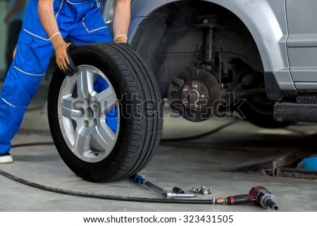 mechanic changing a wheel of a modern car  in a workshop Royalty-Free Stock Photo #323431505