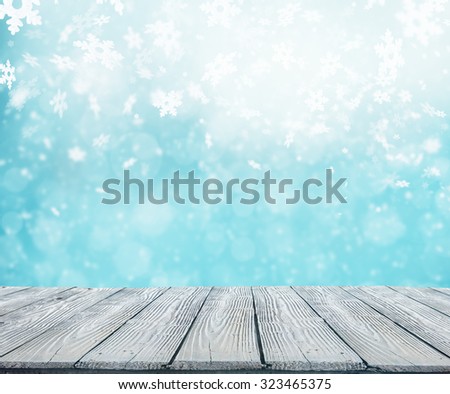 Winter background with pile of snow and blur abstract lights. Empty wooden planks on foreground. Copyspace for text