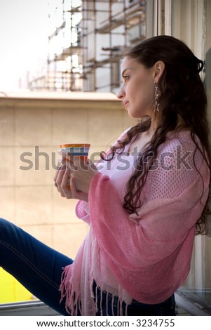 beautiful young woman drinking coffee at the window