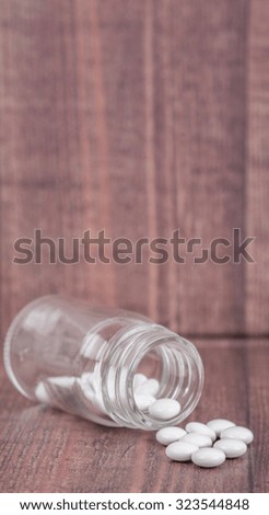 Medicinal pills in a glass bottle over wooden background