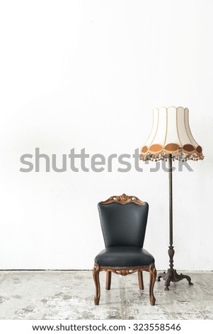 Black vintage armchair and lamp on white wall.