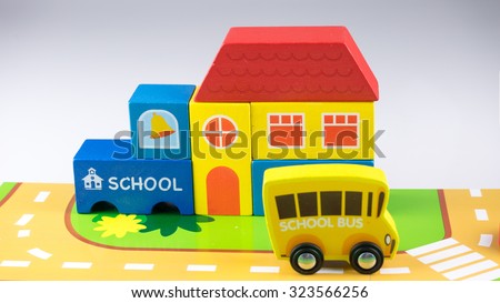 Cute wooden bus stop sign, school building, bushes and single decker school bus. Concept of back to school. Isolated on white background. Slightly de-focused and close-up shot. Copy space.