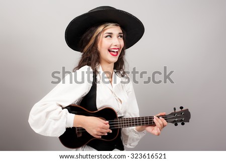 beautiful woman playing guitar with expression in zorro hat