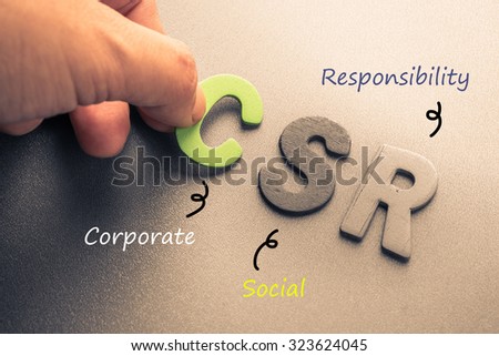 Closeup hand arrange wood letters as CSR abbreviation(Corporate social responsibility) Royalty-Free Stock Photo #323624045