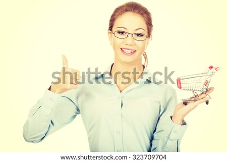 Young businesswoman with shopping cart and thumbs up.