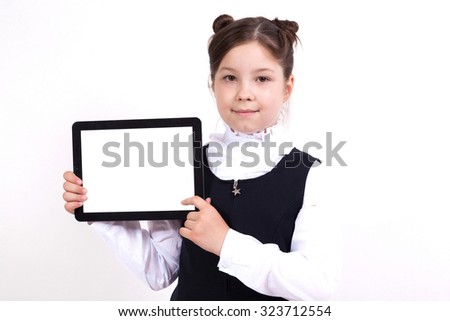 school gir on a white background shows a tablet and smiles picture with depth of field, selective focus on the tablet.