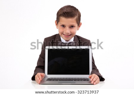 smiling business student at a business suit sitting at his desk and shows laptop, picture with depth of field