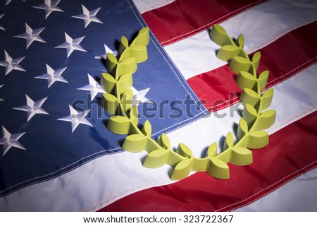 Green laurel wreath sits on the red, white, and blue stars and stripes of an American flag