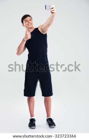 Portrait of a fitness man making selfie photo on smartphone isolated on a white background