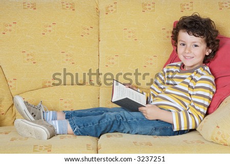 adorable happy boy reading in the armchair of your house