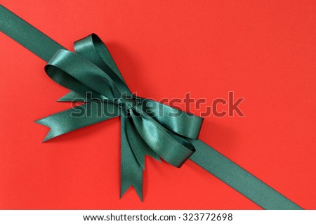 Green gift ribbon bow corner diagonal on red paper background