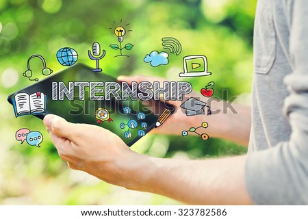 Internship concept with young man holding his tablet computer outside in the park 