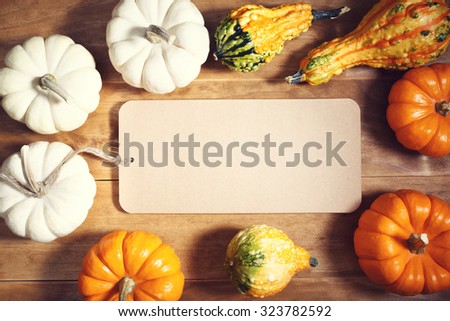 Autumn pumpkins and squashes with message card on wooden table