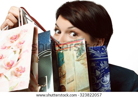 young girl hiding behind a lot of shopping bags with shopping