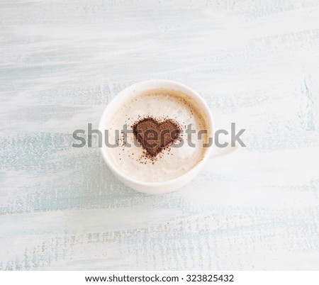 Latte Coffee Cup with Cocoa Heart Shape on Wooden Background
