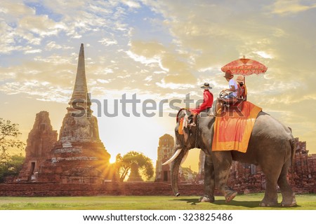  Tourists on an ride elephant tour of the ancient city in sunrise background