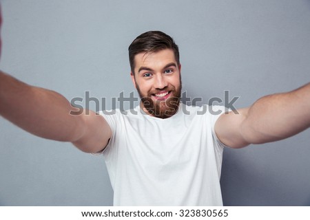 Portrait of a smiling man making selfie photo over gray background