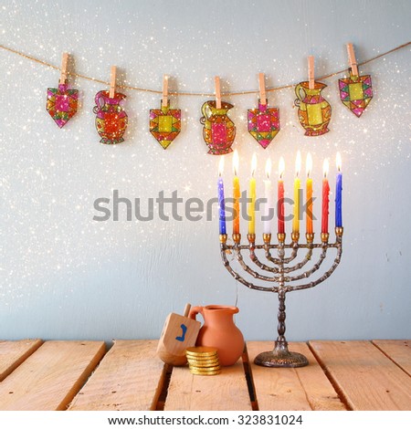 image of jewish holiday Hanukkah with menorah (traditional Candelabra) and wooden dreidels (spinning top). glitter overlay 