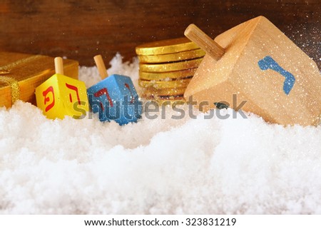 image of jewish holiday Hanukkah with wooden colorful dreidels (spinning top) and chocolate traditional coins over december snow. copy space 