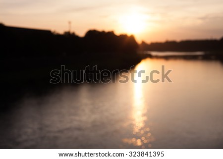 Blurred view of river with trees on the banks with bokeh effect reflected on water