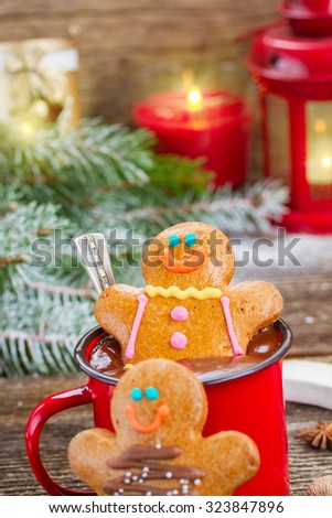 two  Gingerbread men with mug of  chocolate and glowing lanterns and christmas tree