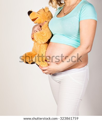 Young pregnant woman with  toy on her belly