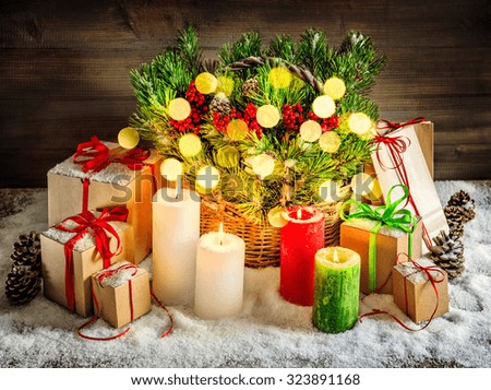 Christmas decoration burning candles and gift boxes. Christmas tree branches in basket. Vintage style toned picture with light effects. Vibrant colors