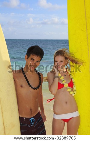 Hawaiian beach boy and young blond woman in a bikini with surfboard
