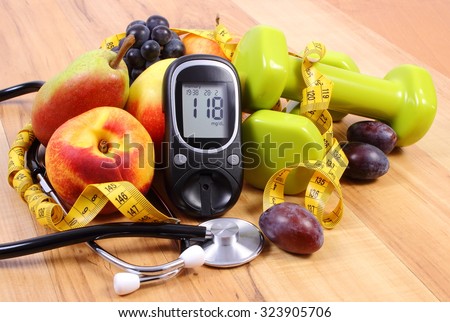 Glucose meter with medical stethoscope, fruits and dumbbells for using in fitness, concept of diabetes, healthy lifestyles and nutrition Royalty-Free Stock Photo #323905706