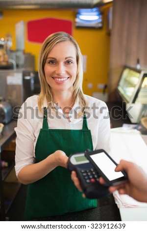 Portrairt of female worker accepting payment from customer through NFC in bakery