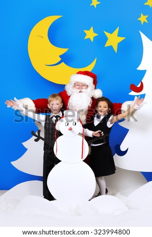 Santa Claus standing with happy children in a cartoon fairy snowy forest. Full length portrait.