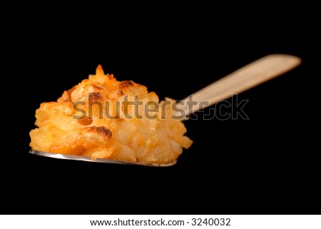 A spoonful of macaroni and cheese on black background with shallow depth of field