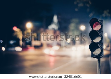 Red traffic light on the road in night city. dangerous signal stop crash driving highway,expressway; Blurred background of car dark fast truck surveillance security with semaphore. safety street Royalty-Free Stock Photo #324016601