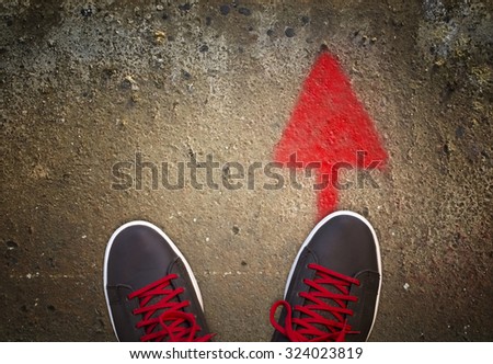Sneakers standing on a road with arrow