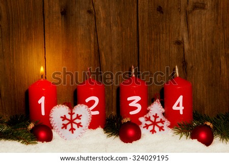 Advent candles with snow in front of wood background Royalty-Free Stock Photo #324029195