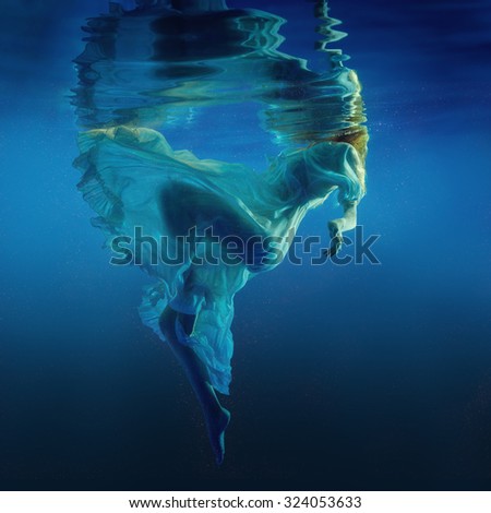 The girl in a beautiful dress under water.