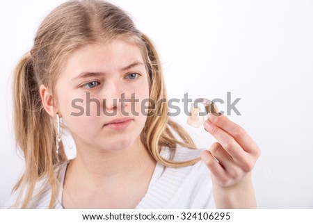 Young girl checking her hearing aid. Focused on the hearing aid.