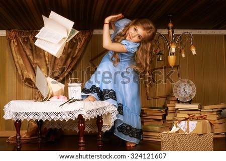 Little girl in a blue dress in little room with a books